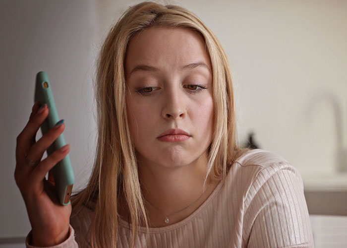Young woman looking upset while holding phone, illustrating conflict as man refuses to let her marry in his yard.