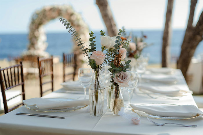 Elegant wedding venue table setup with floral centerpieces by the ocean, highlighting woman refuses to cancel dream wedding venue.