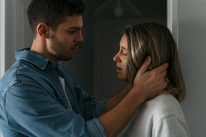 Man holding a woman’s face in a tense moment, illustrating everyday sexism and pressure women experience.