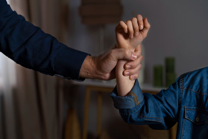 Man grabbing a woman's wrist tightly, illustrating examples of everyday sexism and pressure women face as normal behavior.