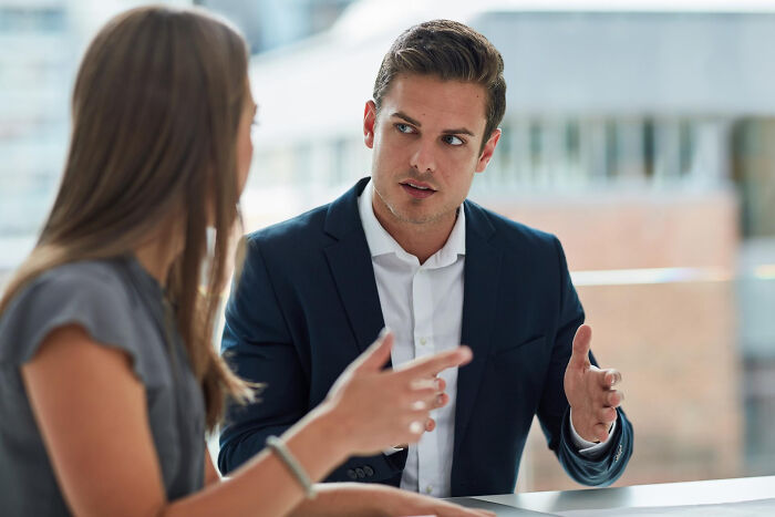 Man and woman in a business discussion illustrating examples of everyday sexism and pressure women face at work.