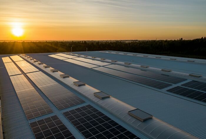 Solar panels on a rooftop at sunrise, symbolizing sustainable energy and good news in environmental progress.