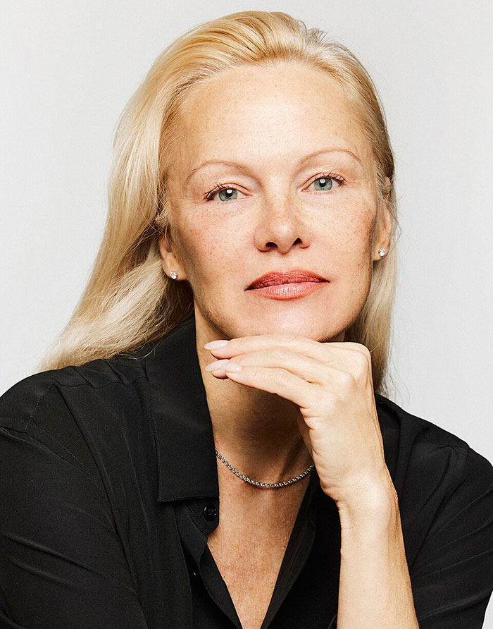 Pamela Anderson posing thoughtfully with her hand under chin in a black shirt, breaking silence on cooking show accusations. - 1