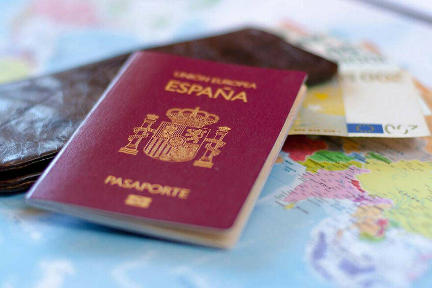 Spanish passport on a travel map with money and wallet, illustrating expired passport and home alone vibes incident.
