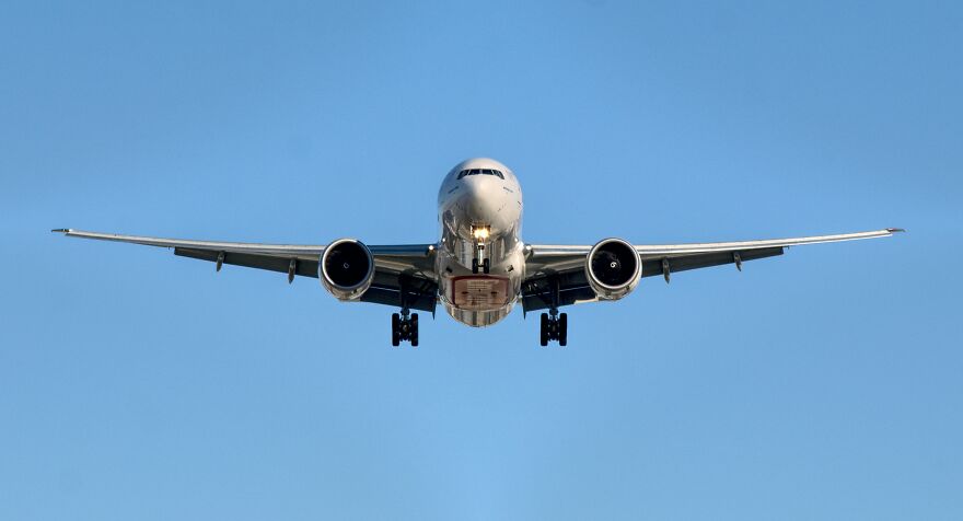 Commercial airplane landing against clear blue sky, illustrating home alone vibes at airport with child left behind.