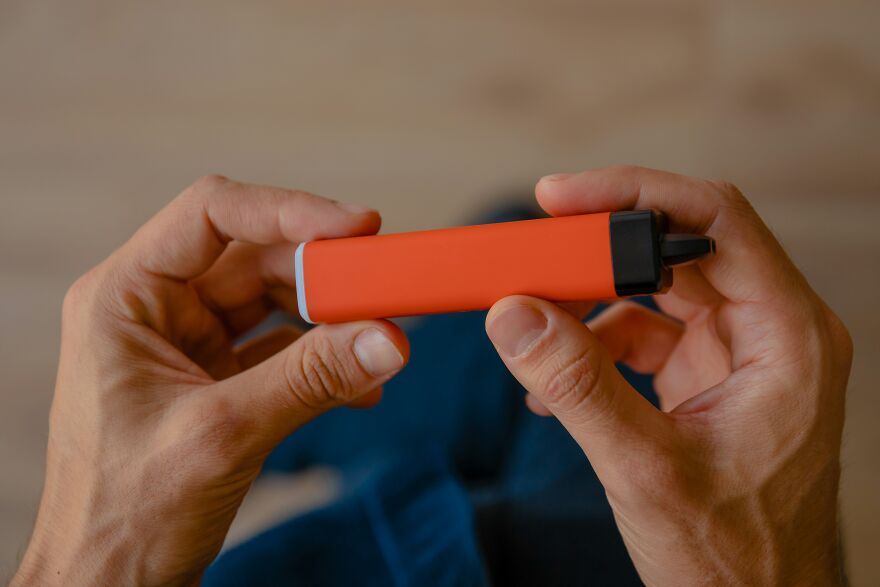 Close-up of a man holding a small red device, related to sparks and in-flight showdown involving breaking the law in bathroom. Close-up of a man holding a small red device, related to sparks and in-flight showdown involving breaking the law in bathroom.