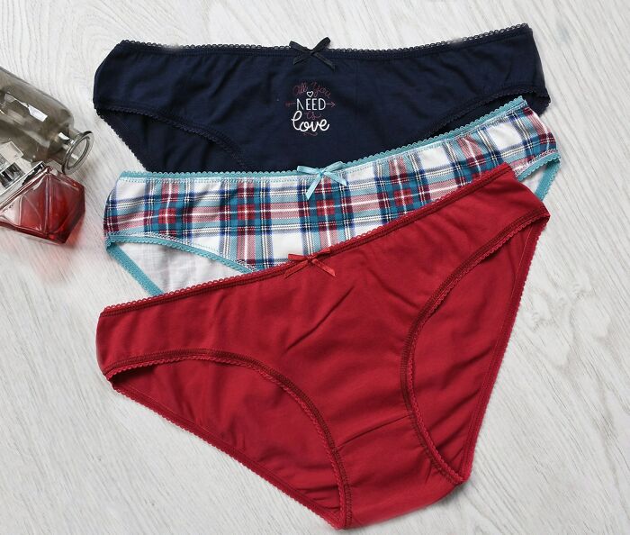 Three pairs of women's underwear in navy, plaid, and red laid out next to perfume bottles as unexpected wedding registry items.