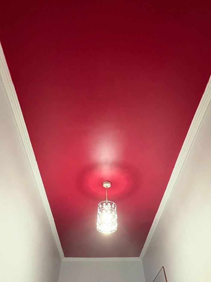 Ceiling light fixture with a decorative shade hanging from a bold red painted ceiling in home decor piece.