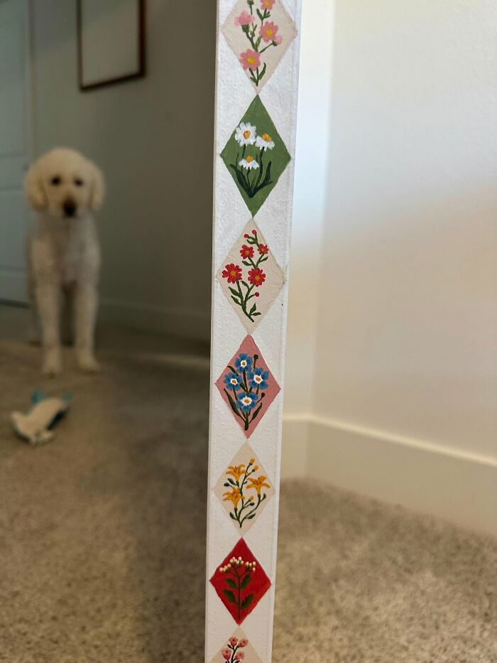 Hand painted floral decor piece on white surface with a blurred dog in the background enhancing home magic.