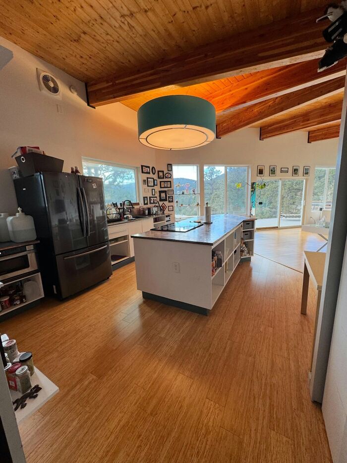 Modern kitchen with wooden floors and ceiling, large island, and decor pieces enhancing a magical home atmosphere.