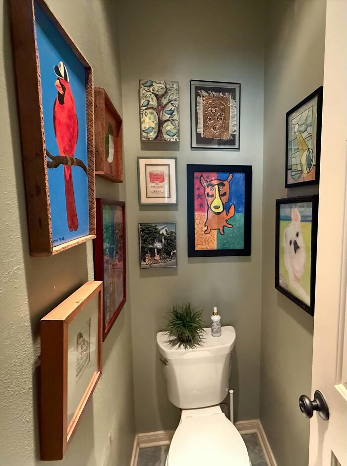 Small bathroom decorated with colorful framed artwork and unique decor pieces creating a magical home atmosphere.