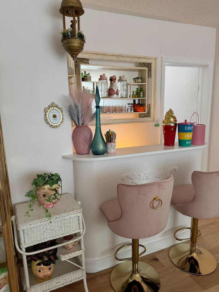 Cozy home bar area with pink velvet stools, decorative vases, and whimsical decor pieces enhancing the magical home ambiance.