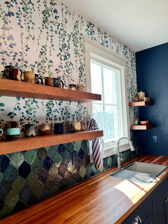 Cozy kitchen space featuring unique decor pieces with wooden shelves, patterned backsplash, and vibrant wallpaper accents.