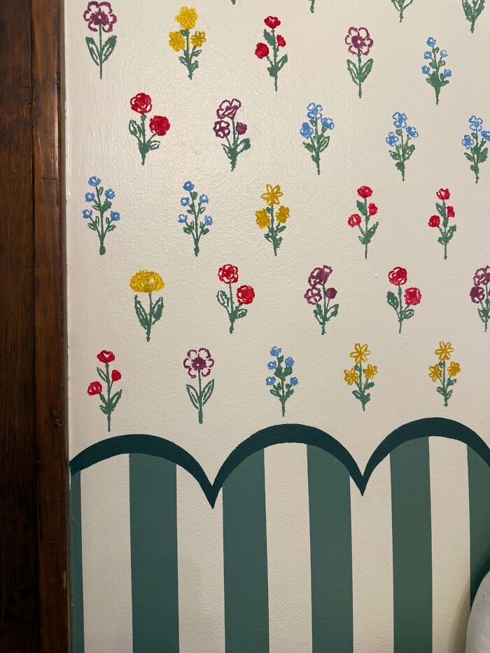 Hand-painted floral decor piece on white wall above green striped furniture, adding a magical home decor touch.