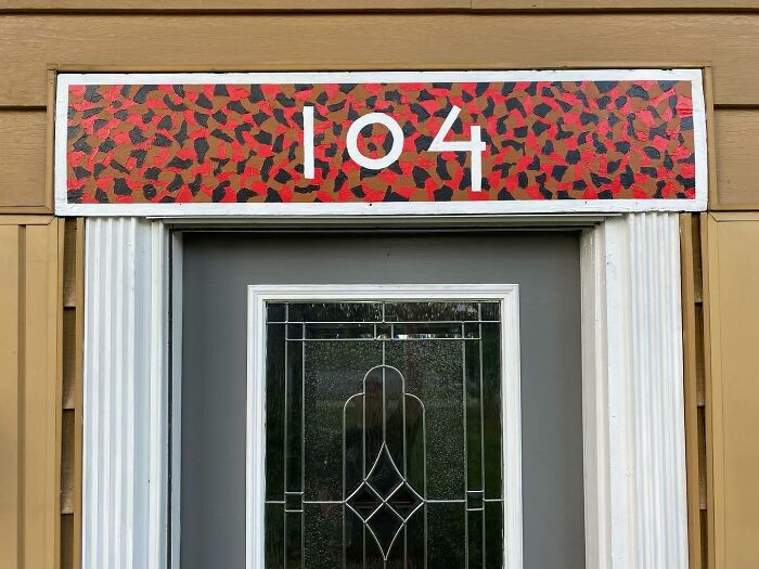 House entrance with decorative glass door and artistic decor piece displaying number 104 above the doorframe.