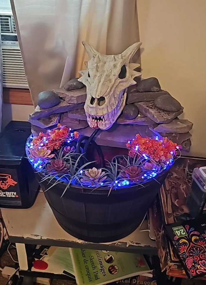 Dragon skull decor piece with blue fairy lights and faux flowers in a rustic pot enhancing magical home decor.
