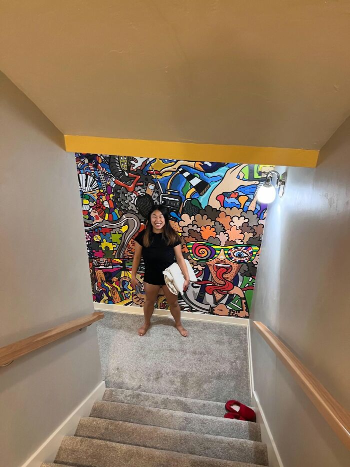 Woman standing at the bottom of stairs with colorful artistic wall decor piece adding a magical touch to the home interior.