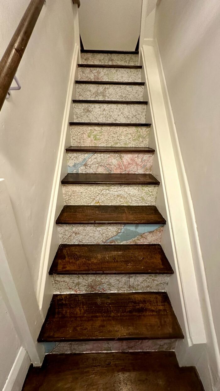 Staircase with wooden steps and map-patterned decor pieces on risers creating a magical home atmosphere.