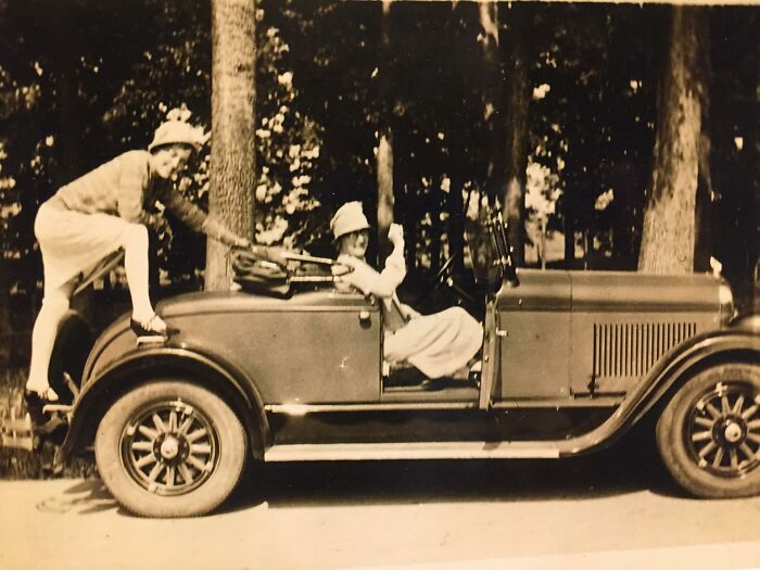 Vintage photograph of two people playing on an old car, evoking nostalgia and unique decor pieces for magical homes.