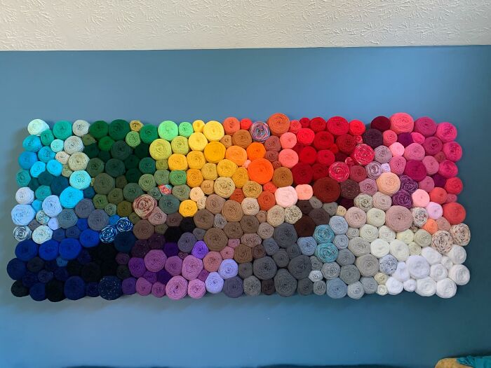 Colorful rolled fabric decor pieces arranged in a rainbow pattern on a blue wall, enhancing home magical decor vibes.