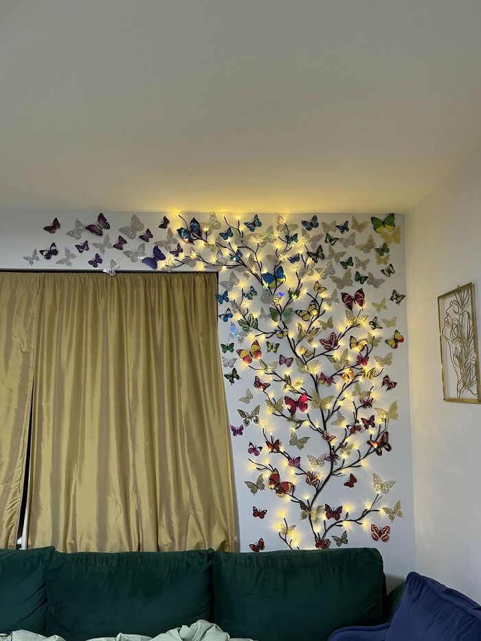 Butterfly wall decor with string lights creating a magical atmosphere in a cozy living room setup.