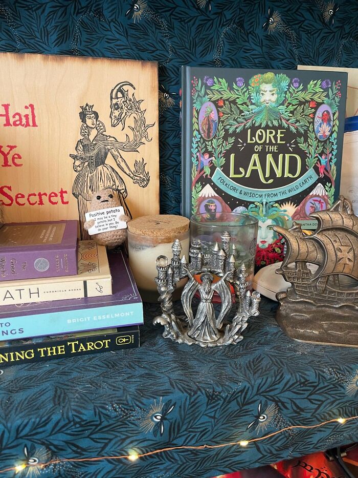 Magical decor pieces including folklore book, tarot guide, candle, and vintage-style figurines creating a magical home atmosphere.