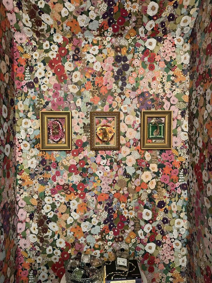 Vibrant floral wallpaper with three framed decor pieces and decorative bottles enhancing a magical home space.