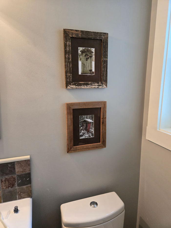 Rustic framed decor pieces hanging on a pale wall above a toilet, adding magical charm to the home interior.