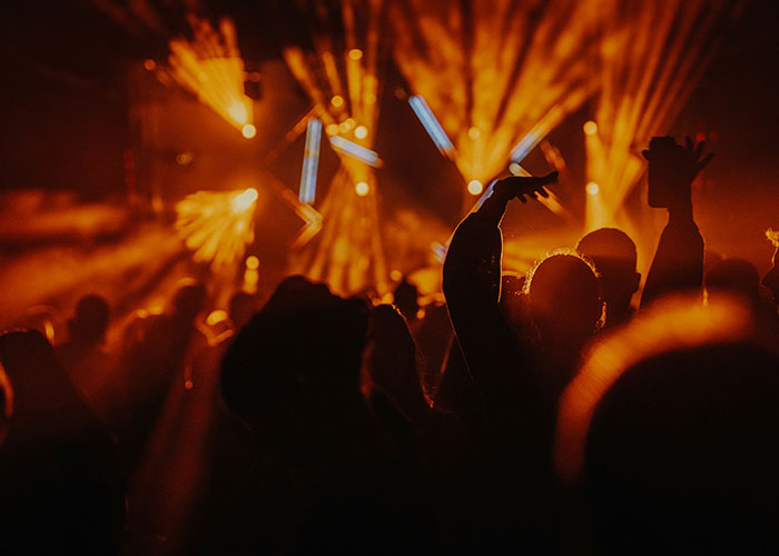 Crowd at a concert with orange stage lights highlighting silhouettes, capturing the mysterious atmosphere of unexplained events.