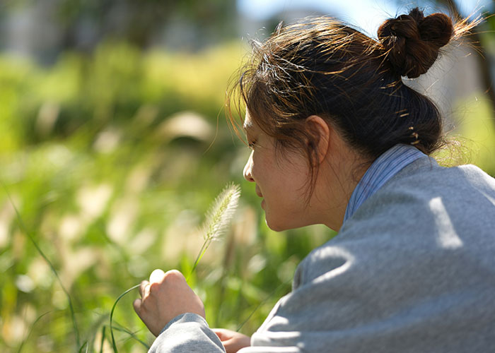 Young woman in a gray jacket exploring nature, reflecting on unexplained mysteries people experienced firsthand outdoors.