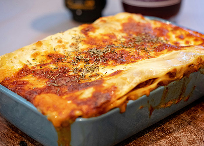Close-up of a baked lasagna with melted cheese and herbs, capturing a homemade mystery food experience.
