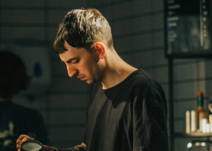 Young man focused and thoughtful, captured in dim light, evoking the mystery and personal experience theme.