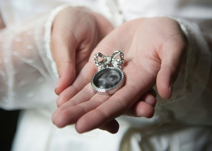 Hands holding a vintage photo locket symbolizing personal mysteries people experienced and still can’t explain.