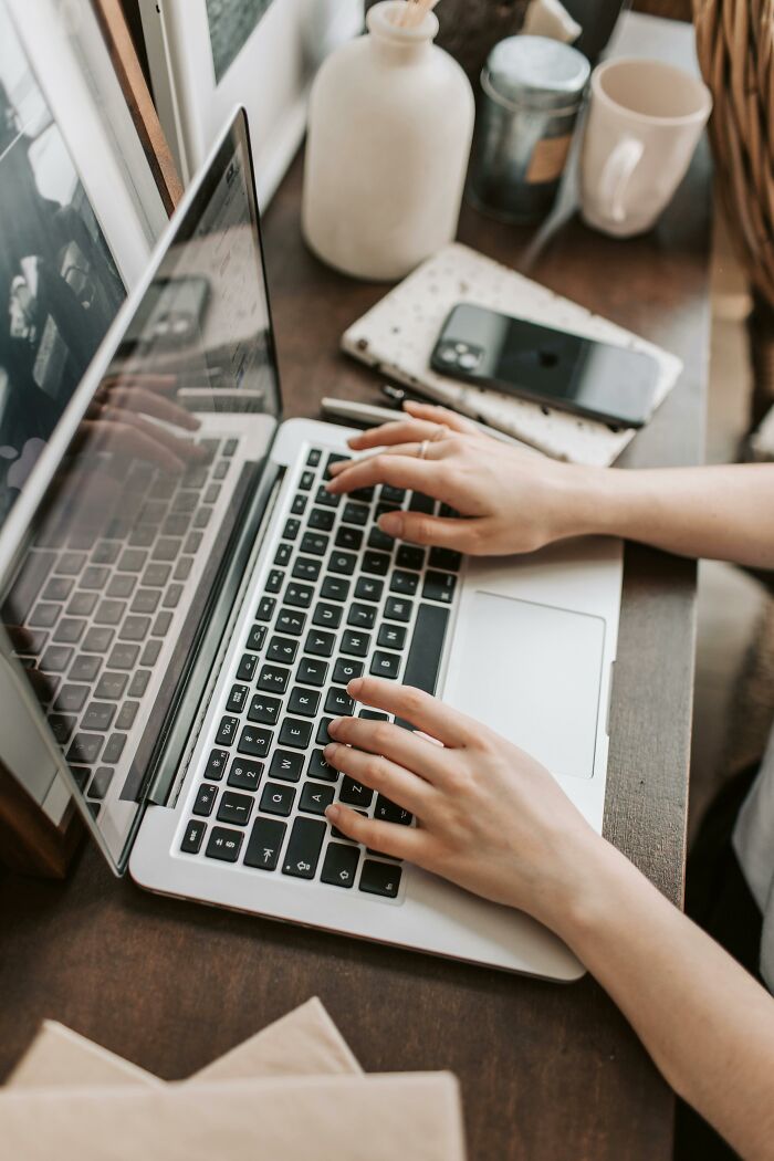 Person typing on laptop at wooden desk with phone and mug nearby showing industry secrets being shared online - 10