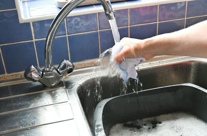Person washing a cloth under running water in a kitchen sink, illustrating industry secrets being shared. - 3