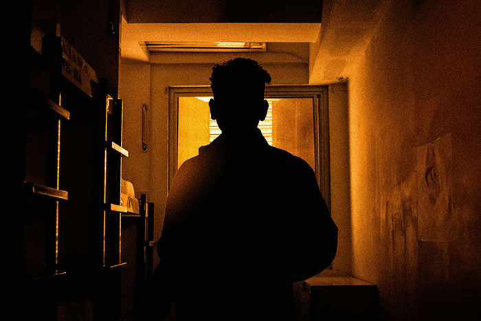 Silhouette of a person standing in a dimly lit hallway, creating a creepy atmosphere for the eerie experience theme.