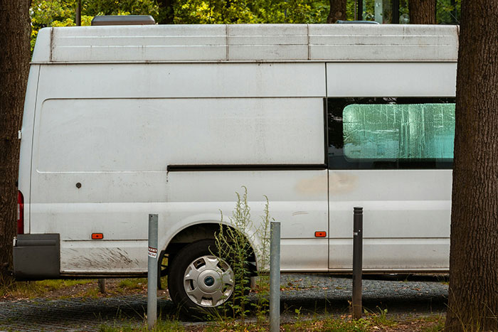 White van parked near trees and metal poles, evoking creepy experiences people still think about from time to time.