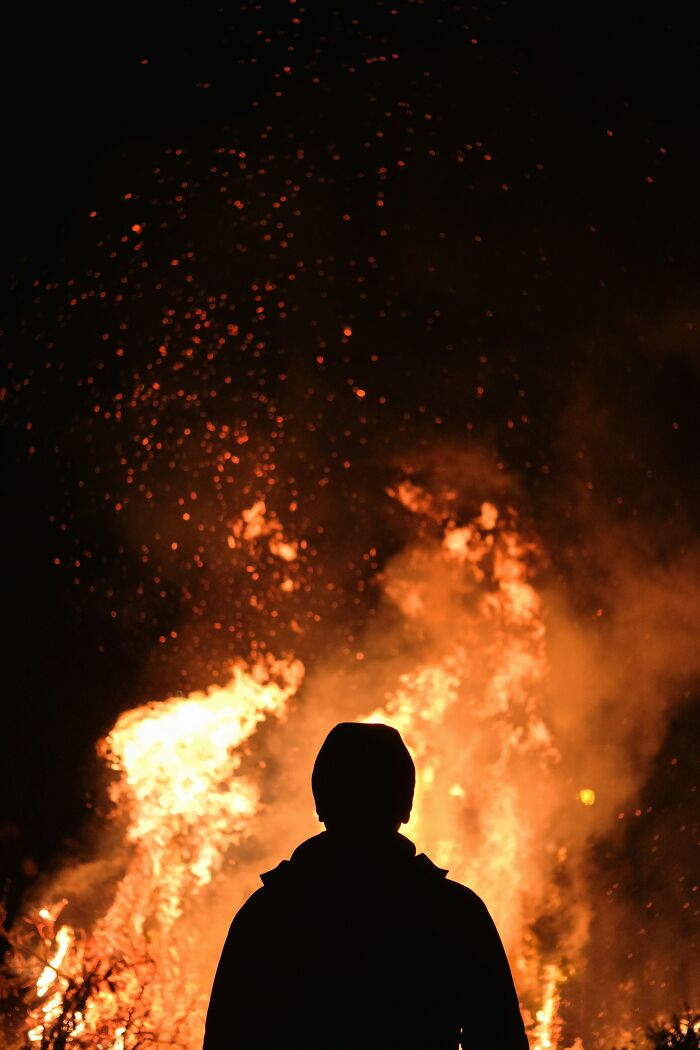 Silhouette of a person standing in front of a large fire, illustrating things people thought were a flex but actually aren’t.