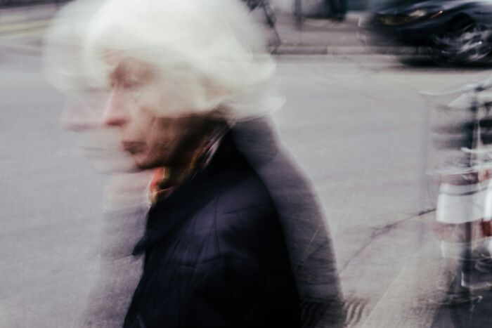 Blurred image of an elderly person walking on a city street, reflecting unsettling and disturbing facts shared by people.