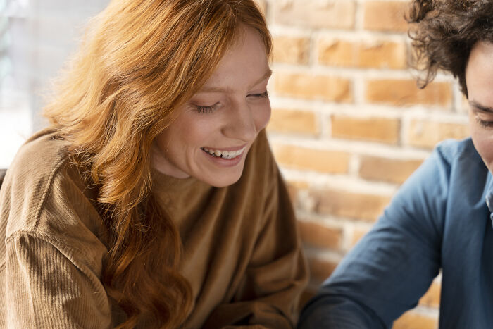 Two people smiling and talking together in a cozy setting, illustrating unique words used in other languages.