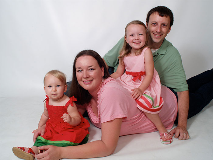 Family of four smiling together, illustrating the human side of working at an overworked and underpaid dying company.