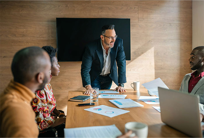 Man in a business suit leading a tense meeting with colleagues, illustrating the challenges of working at an underpaid company.
