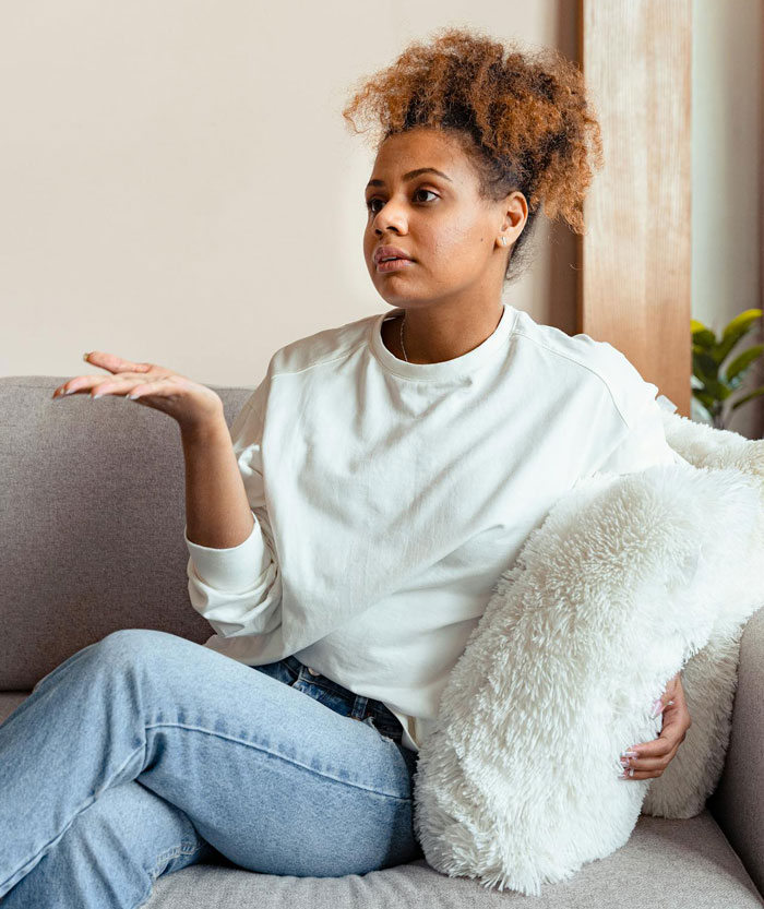 Nonbinary person sitting on couch with fluffy pillow, expressing refusal to share private bathroom with roommates’ boyfriends Nonbinary person sitting on couch with fluffy pillow, expressing refusal to share private bathroom with roommates’ boyfriends