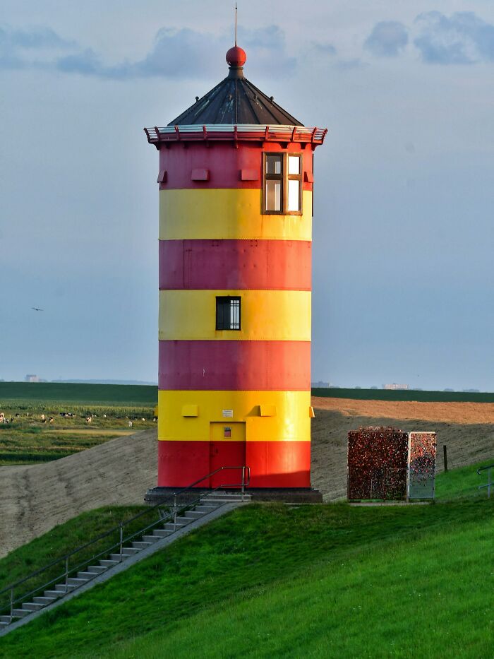 Colorful lighthouse on a grassy hill at dusk, evoking eerie atmosphere for night shift workers' paranormal encounters.