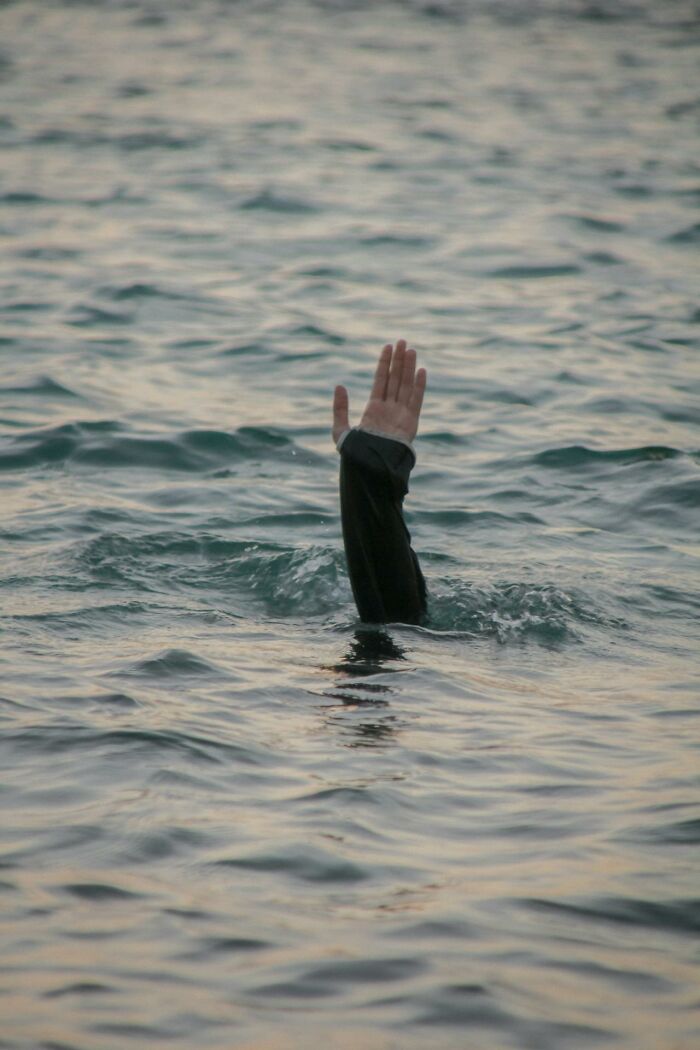 A person raising a hand above water, illustrating people surviving crazy situations in a dangerous environment.
