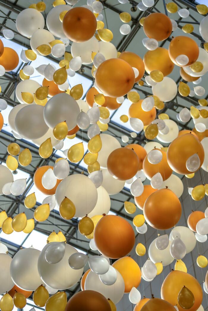 Orange, white, and gold balloons suspended from a ceiling, illustrating PR campaigns and decisions failures visually.