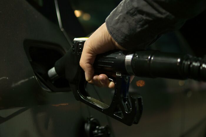 Hand holding a gas pump nozzle fueling a vehicle, illustrating a tiny human mistake that impacted history.