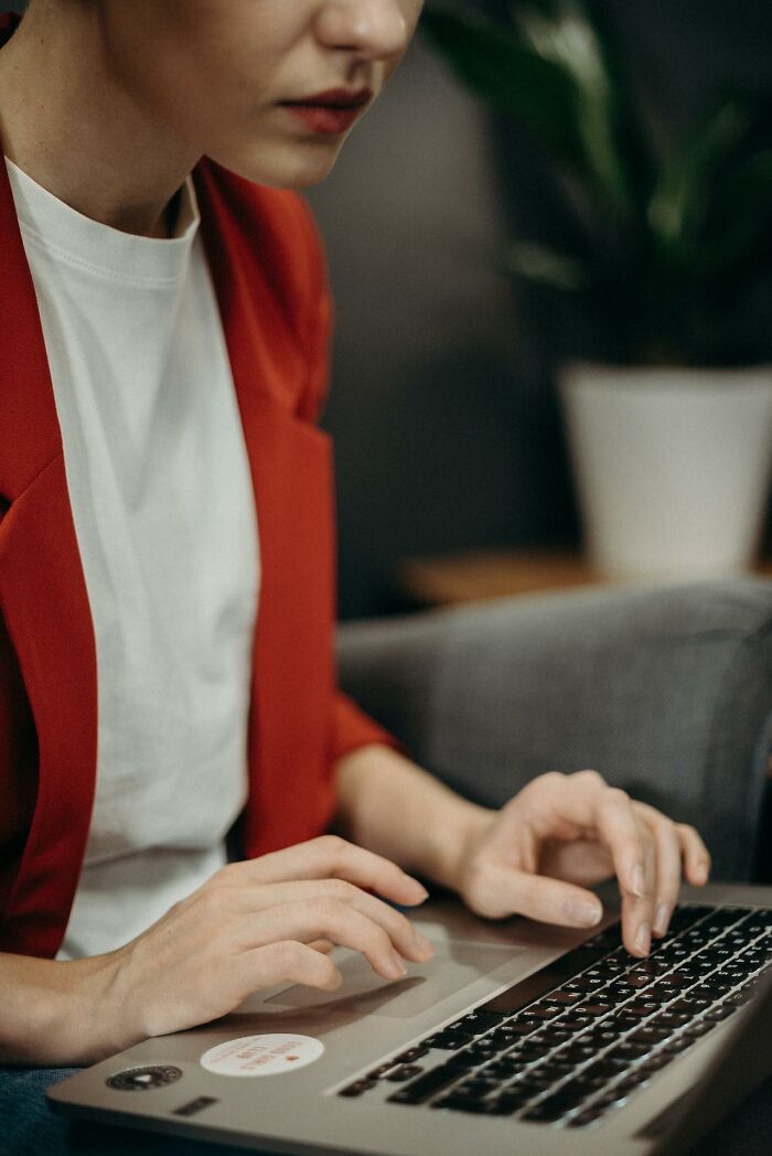 Person in red jacket typing on a laptop researching some of the world’s greatest unsolved mysteries online.