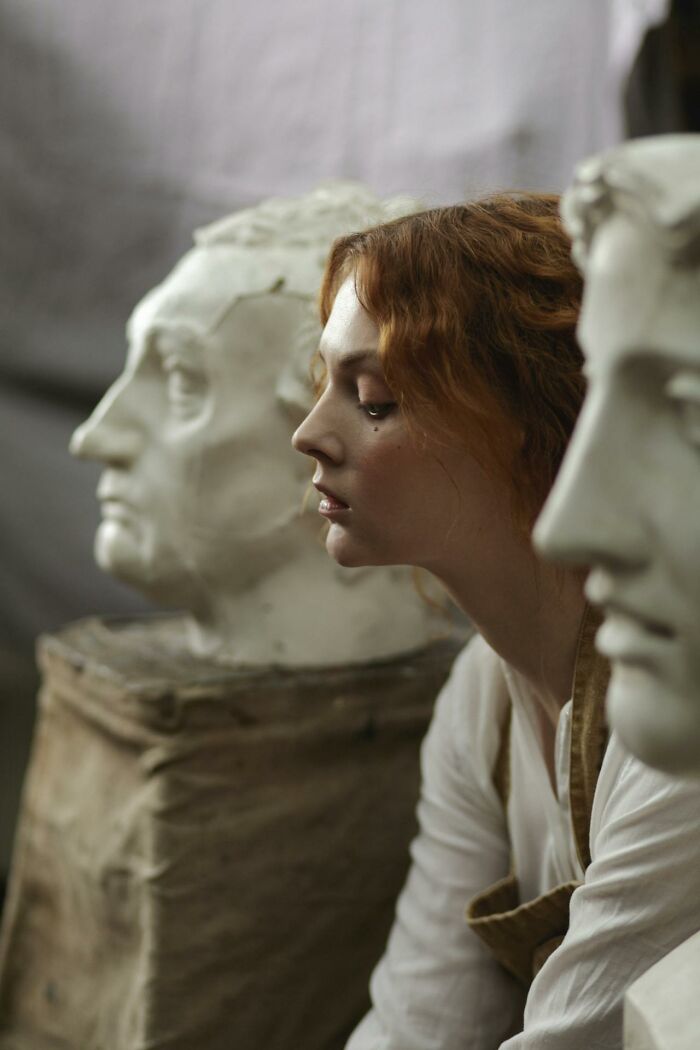 Young woman examining classical sculpture heads, symbolizing reflection on what made them realize they’re talking to a psychopath.