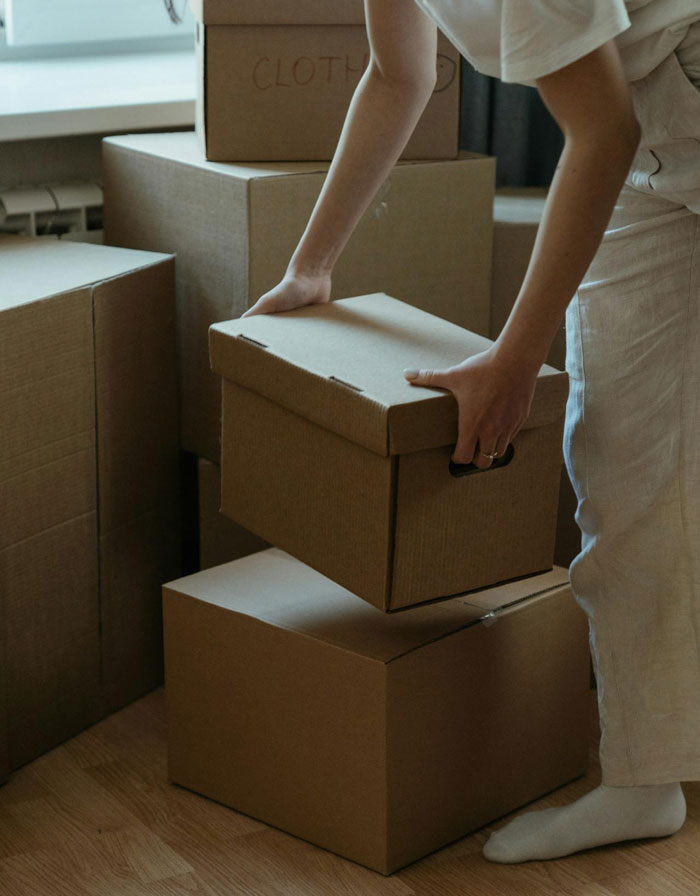 Person arranging cardboard boxes inside a house, illustrating a friend breaking into house and planting stuff to prove residency.